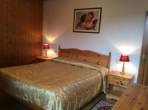 a bedroom with a bed and two night stands with lamps at Residenze Sonnenschein Casa Bianca in Villabassa