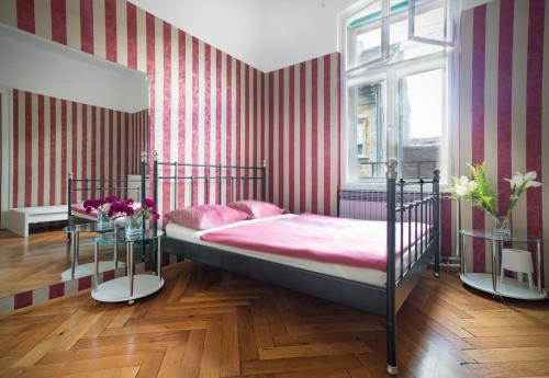 a bedroom with a bed with pink sheets and striped walls at Guesthouse Centar 2 in Zagreb