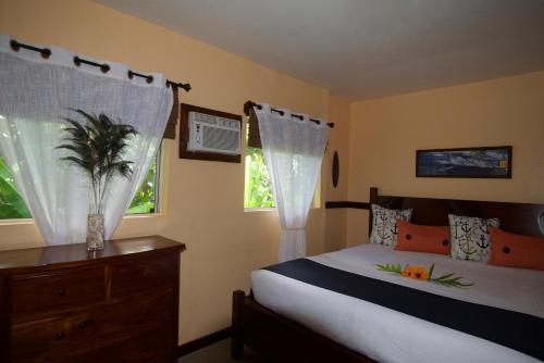 a bedroom with a bed and a dresser and two windows at Kalani Hawaii Private Lodging in Pupukea