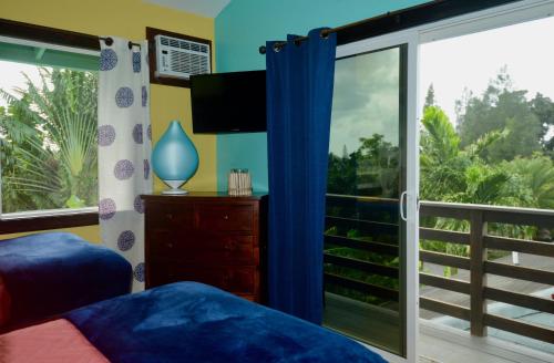 a bedroom with a sliding glass door with a balcony at Kalani Hawaii Private Lodging in Pupukea
