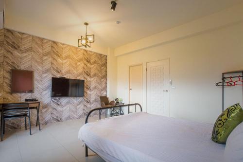 a bedroom with a bed and a desk and a television at Alan's House B&B in Jiaoxi