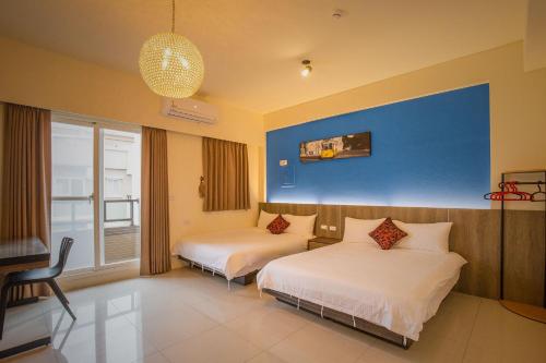 - une chambre avec 2 lits et un mur bleu dans l'établissement Alan's House B&B, à Jiaoxi