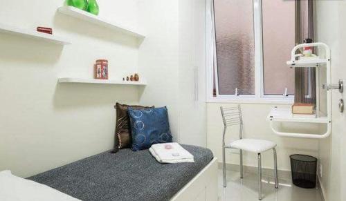 Mały, biały pokój z ławką i krzesłem w obiekcie Suítes e Quartos na Avenida Carlos Gomes w mieście Porto Alegre