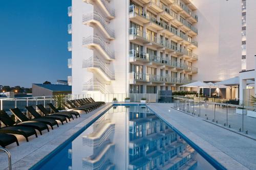 un hotel con piscina con sillas y un edificio en Art Series - The Watson, en Adelaida