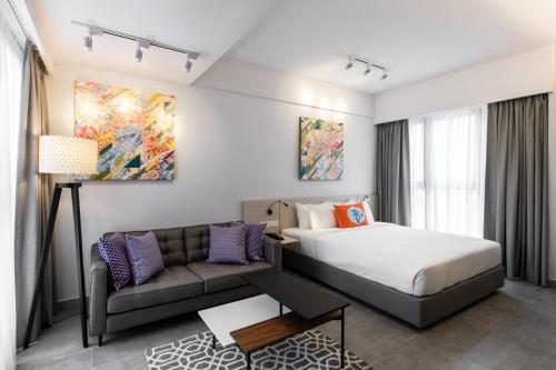 a hotel room with a bed and a couch at The Canvas Hotel in Klang