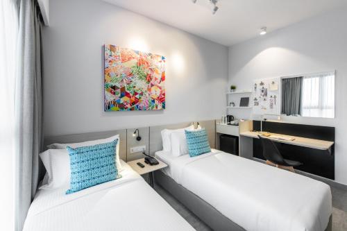 um quarto de hotel com duas camas e uma secretária em The Canvas Hotel em Klang