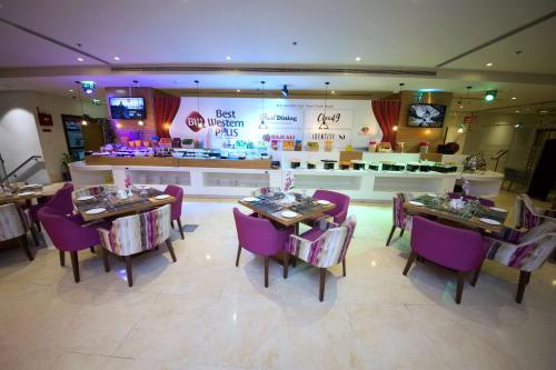 a restaurant with tables and purple chairs and a counter at Best Western Plus Pearl Creek in Dubai