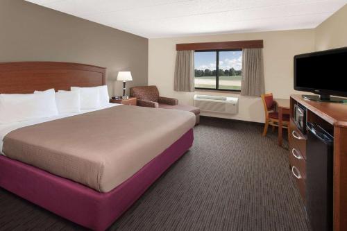 a hotel room with a bed and a flat screen tv at AmericInn by Wyndham Grundy Center in Grundy Center