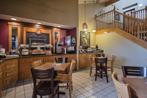 a restaurant with tables and chairs and a staircase at AmericInn by Wyndham Grundy Center in Grundy Center