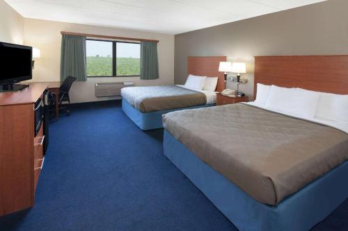 a hotel room with two beds and a flat screen tv at AmericInn by Wyndham Webster City in Webster City