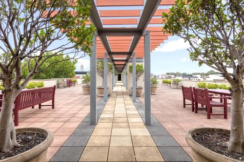a walkway with benches and trees on a building at Nesuto Chippendale in Sydney