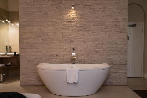 a bath tub in a bathroom with a brick wall at Vue Grand Hotel in Queenscliff