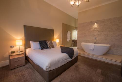 a bedroom with a large bed and a bath tub at Vue Grand Hotel in Queenscliff