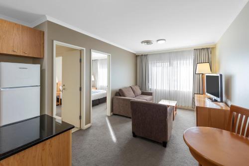 sala de estar con sofá, mesa y cocina en Nesuto Canberra, en Canberra