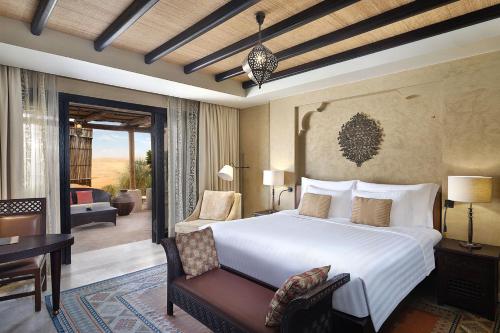 a bedroom with a large bed and a living room at Anantara Qasr al Sarab Desert Resort in Jurayrah
