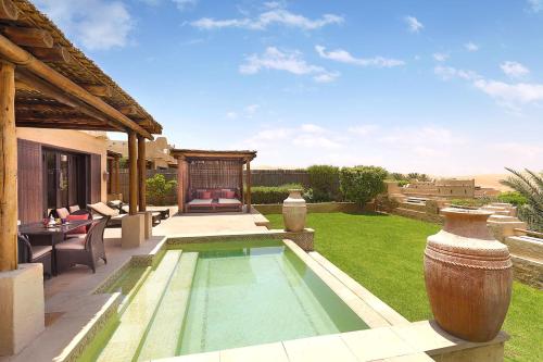 a backyard with a swimming pool and a house at Anantara Qasr al Sarab Desert Resort in Jurayrah