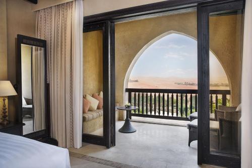 a bedroom with an open door to a balcony at Anantara Qasr al Sarab Desert Resort in Jurayrah