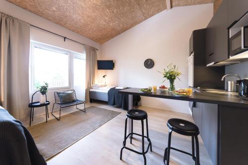 - une cuisine et un salon avec un comptoir et des tabourets dans l'établissement Spot Apartments Uusmäki, à Espoo