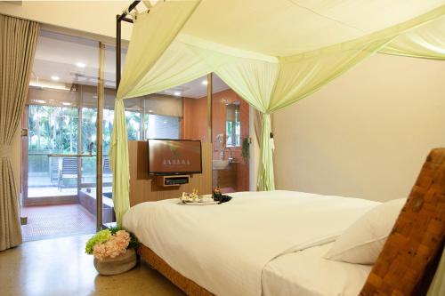 a bedroom with a canopy bed with a television at Luminous Hot Spring Resort & SPA in Luye