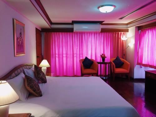 een slaapkamer met een groot bed en roze gordijnen bij Interchange Tower Serviced Apartment - SHA Extra Plus in Bangkok