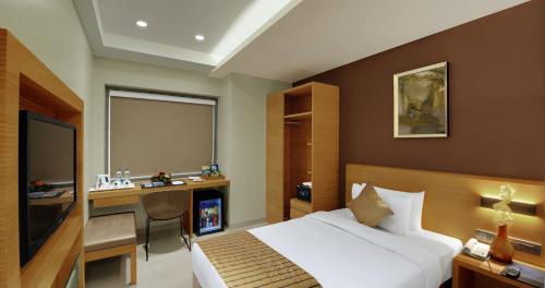 a hotel room with a bed and a desk at Hotel Suba Elite Vadodara in Vadodara