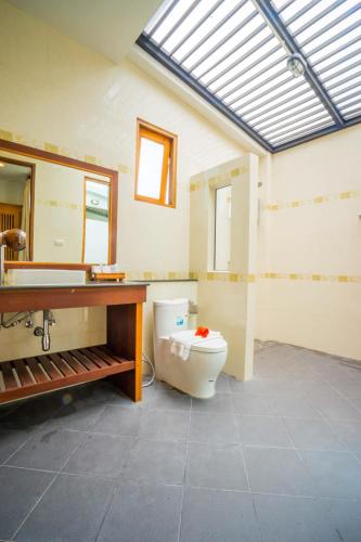 a bathroom with a toilet and a sink and a mirror at Anyamanee Resort in Cha Am
