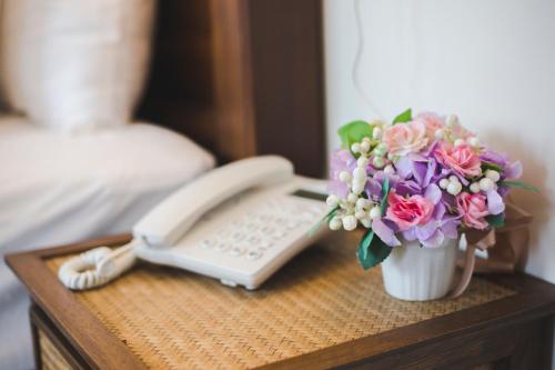a table with a phone and a vase of flowers at Chada Mantra Hotel in Chiang Mai