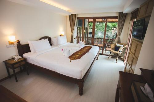 a hotel room with a large bed and a balcony at Chada Mantra Hotel in Chiang Mai