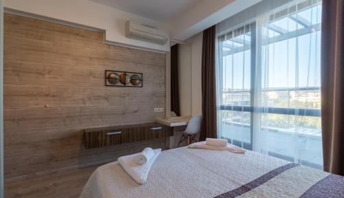 a bedroom with a bed and a window and a desk at City Apartments Triumph in Varna City
