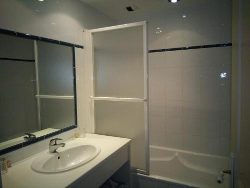a bathroom with a sink and a shower with a mirror at Hôtel du Donjon in Aulnay