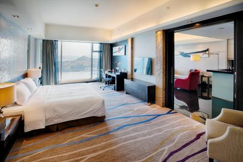 a hotel room with a bed and a large window at Swiss Grand Xiamen-Harbour View in Xiamen