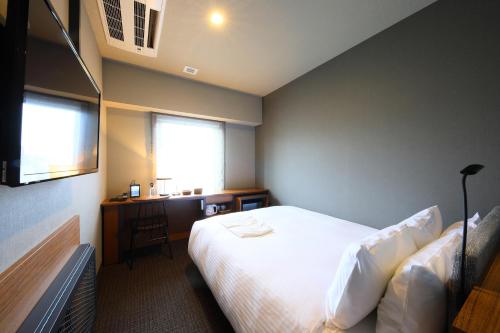 a bedroom with a bed and a desk and a window at ICI HOTEL Ueno Shin Okachimachi in Tokyo