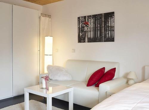 a white living room with a white couch and red pillows at Charmingsuite in Bad Teinach-Zavelstein