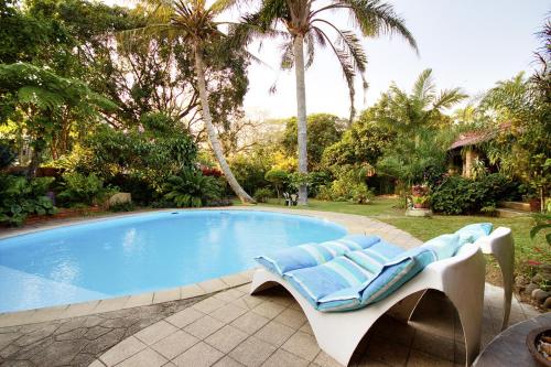 a swimming pool with a lounge chair next to it at Maputaland Guest House in St Lucia