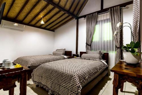 婆羅浮屠的住宿－The Omah Borobudur，一间卧室设有两张床、一张桌子和一个窗口