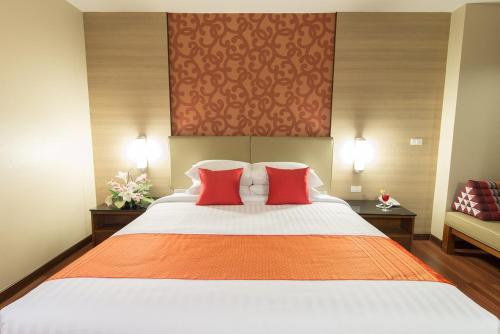 a bedroom with a large bed with two red pillows at Marsi Hotel Bangkok in Bangkok