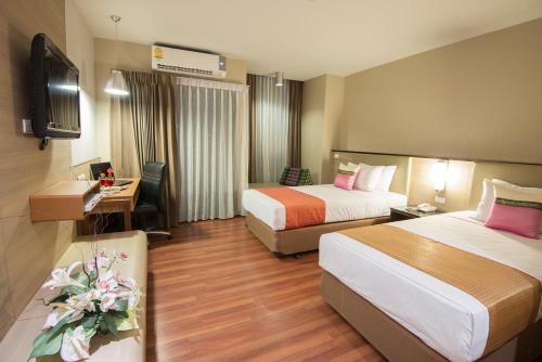 a hotel room with two beds and a desk at Marsi Hotel Bangkok in Bangkok