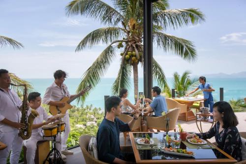 a group of people sitting around a table at a restaurant at Four Seasons Resort Koh Samui - SHA Extra Plus in Mae Nam