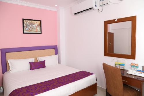 a bedroom with a bed and a desk and a mirror at Sbk Park Inn in Kanchipuram