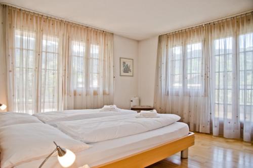 1 dormitorio con 2 camas y ventanas grandes en Apartment Atlanta - GRIWA RENT AG, en Grindelwald
