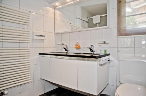 Baño blanco con lavabo y aseo en Apartment Atlanta - GRIWA RENT AG, en Grindelwald