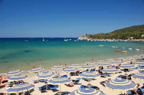 a group of blue and white umbrellas on a beach at Elbamar Procchio in Procchio
