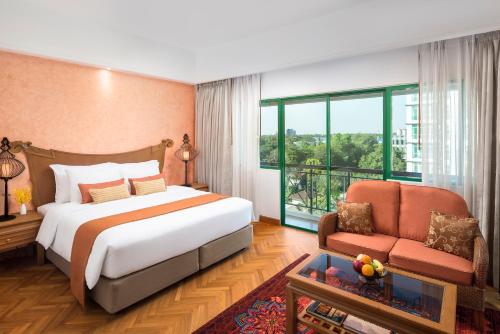 a bedroom with a bed and a chair and a window at Mercure Yangon Kaba Aye in Yangon