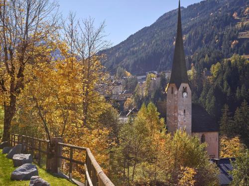 a church with a steeple on a hill with trees at Hapimag Ferienwohnungen Bad Gastein in Bad Gastein