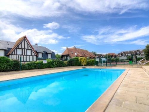 une grande piscine bleue avec des maisons en arrière-plan dans l'établissement CADRE EXCEPTIONNEL: Duplex Classé 4**** Tennis, Piscine, Parking, Linge inclus, WIFI, Matériel BÉBÉ, proximité CENTRE, à Deauville
