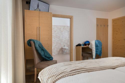 a bedroom with a bed and two chairs and a window at GARNI' Margherita in Predazzo