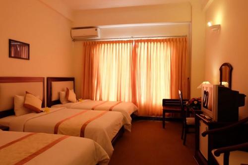 a hotel room with two beds and a television at Indochine Hotel in Kon Tum
