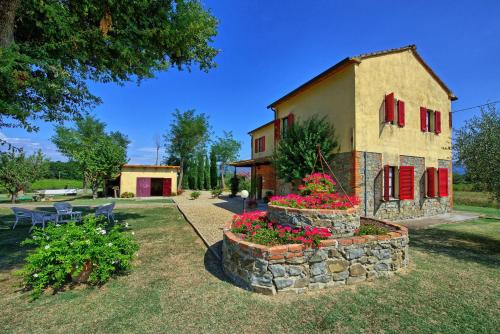 un edificio con persianas rojas y flores en un patio en Agriturismo Podere Delle Querci, en Castiglion Fiorentino