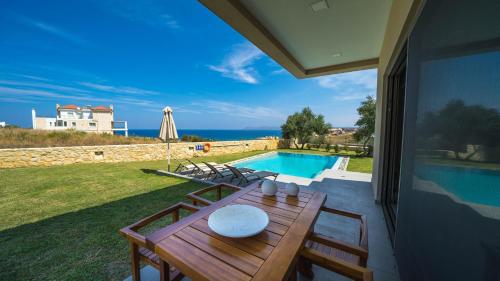 a patio with a table and chairs and a swimming pool at Iskios Villas in Agia Marina Nea Kydonias