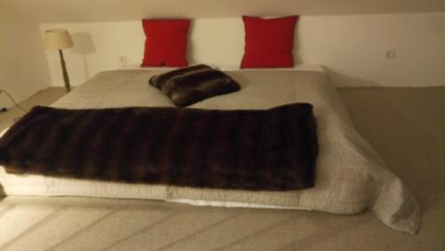 1 cama grande con manta marrón y almohadas rojas en Alter Markt LOFT en Salzburgo